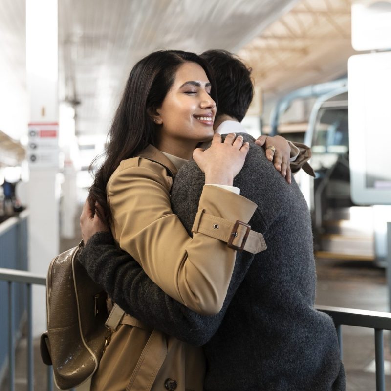 Medium-Shot-Happy-Couple-Hugging-Airport medium-shot-happy-couple-hugging-airport